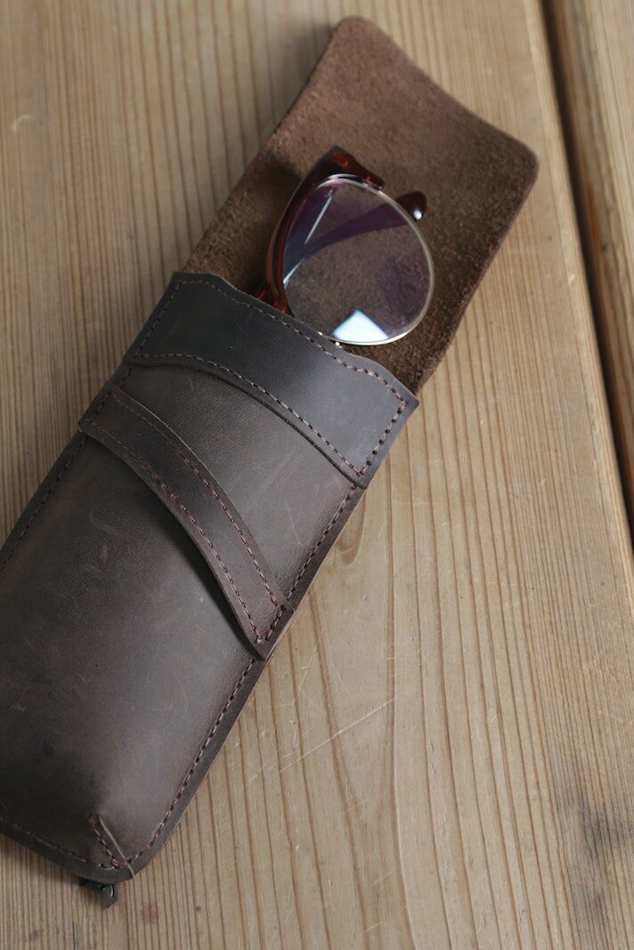 Eyeglasses in Brown Leather Case on Top of Wooden Surface