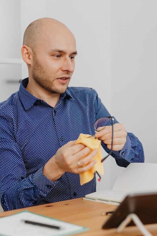 A Man Wiping a Pair of Eyeglasses